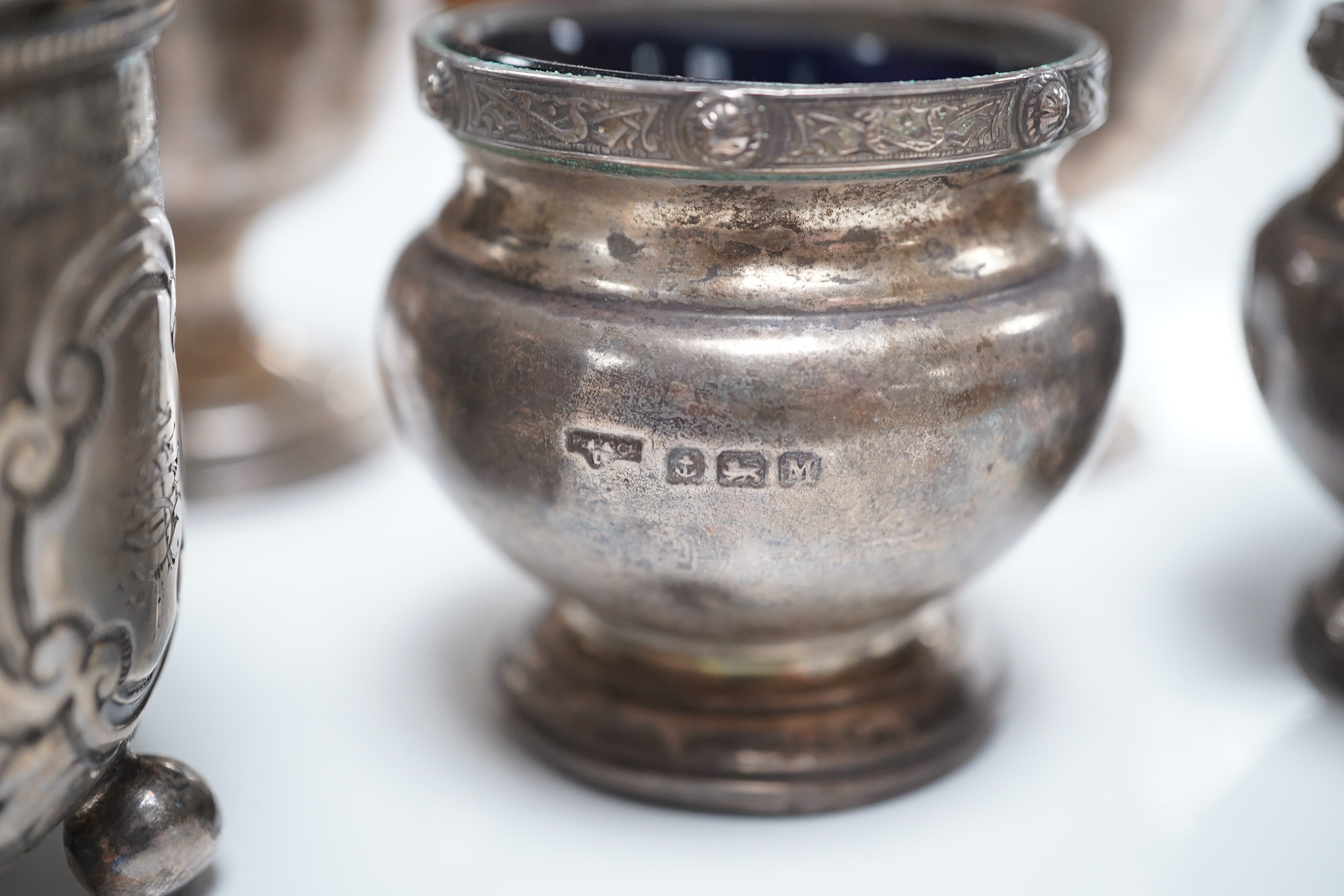 A Victorian repousse silver drum mustard, London, 1887, a silver three piece condiment set, Birmingham, 1936 and a set of three small trophy cups by Mappin & Webb, London, 1925/6. Condition - poor to fair